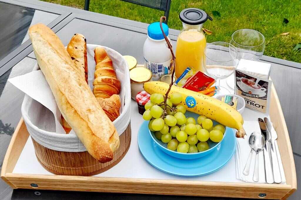 French breakfast tray with baguette, croissants, juice and fruit in the garden